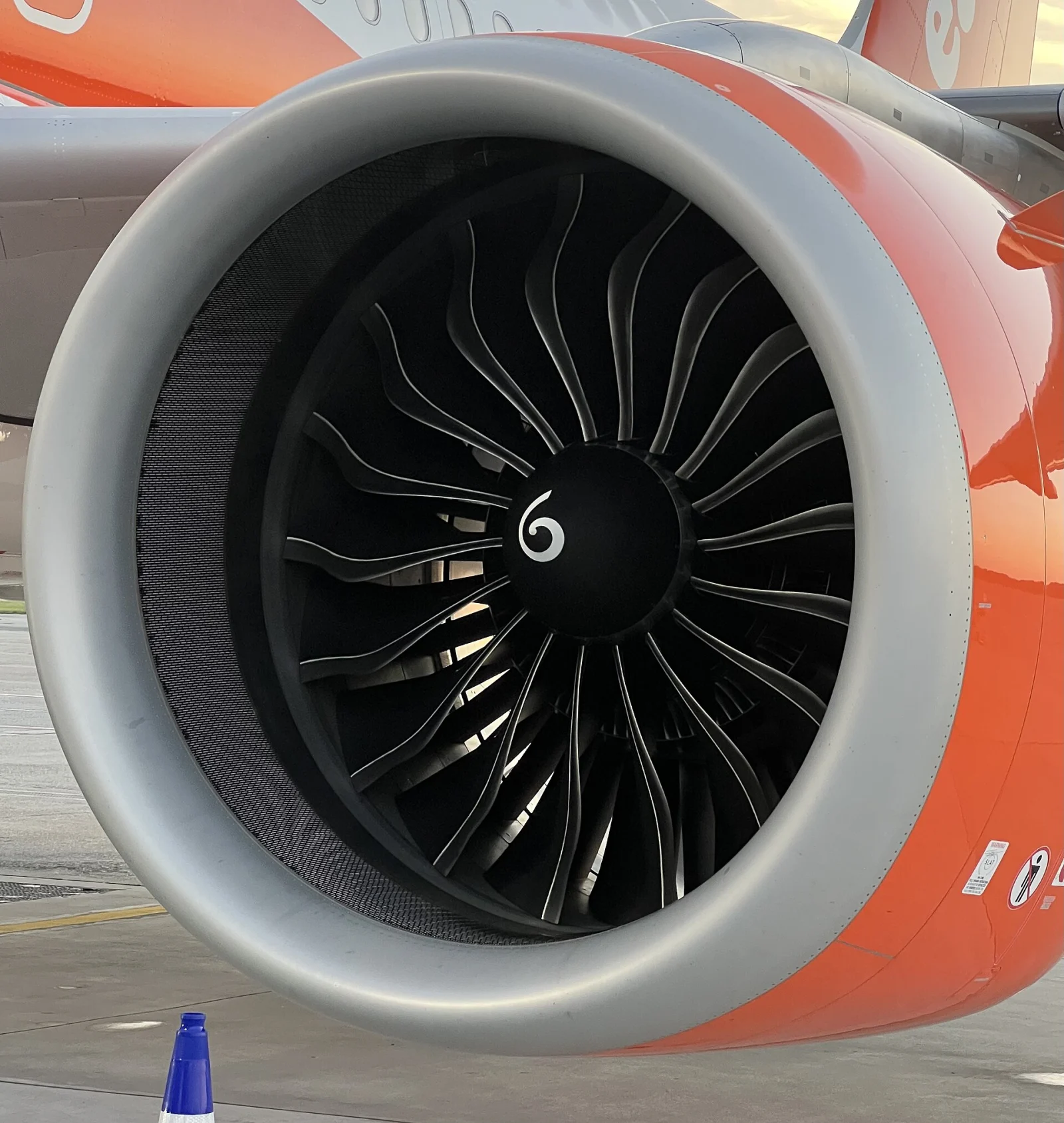 Gros plan sur l’entrée d’air et les pales d’un moteur sous l’aile d’un avion.