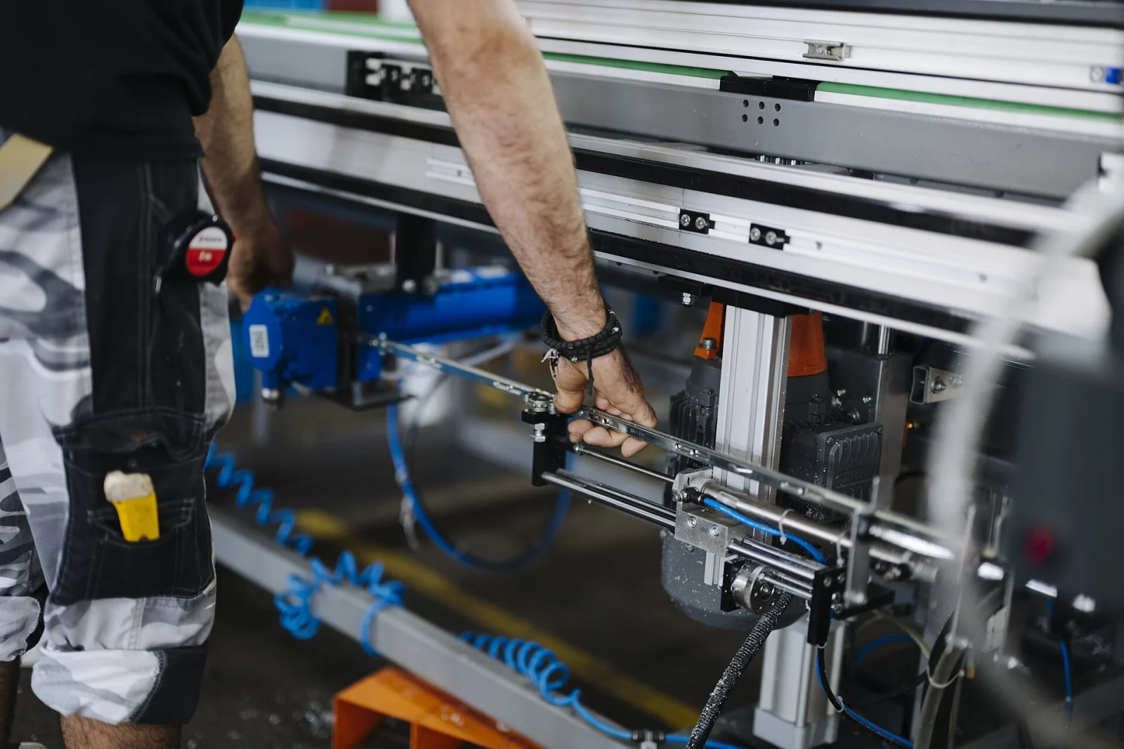 Un ouvrier ajuste une machine avec des outils dans un atelier.