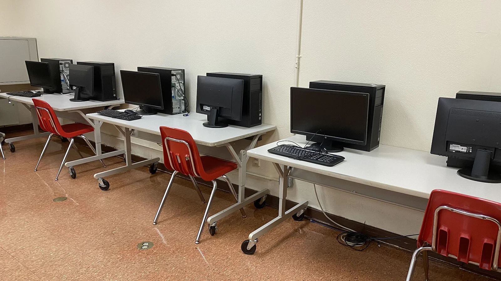 Plusieurs postes informatiques install&eacute;s sur des tables dans une salle informatique.