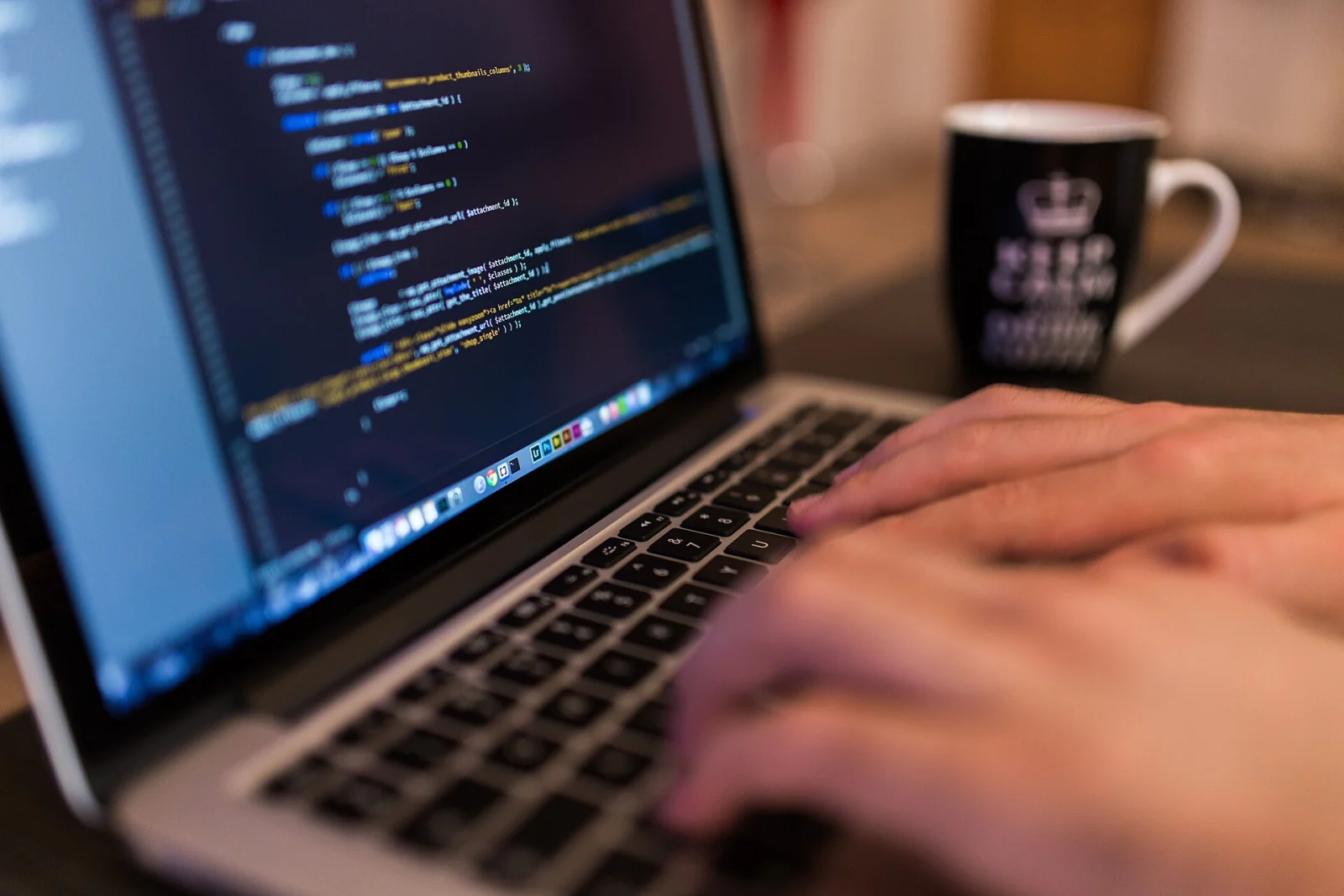 Une personne tape sur le clavier d’un ordinateur portable affichant du code informatique.