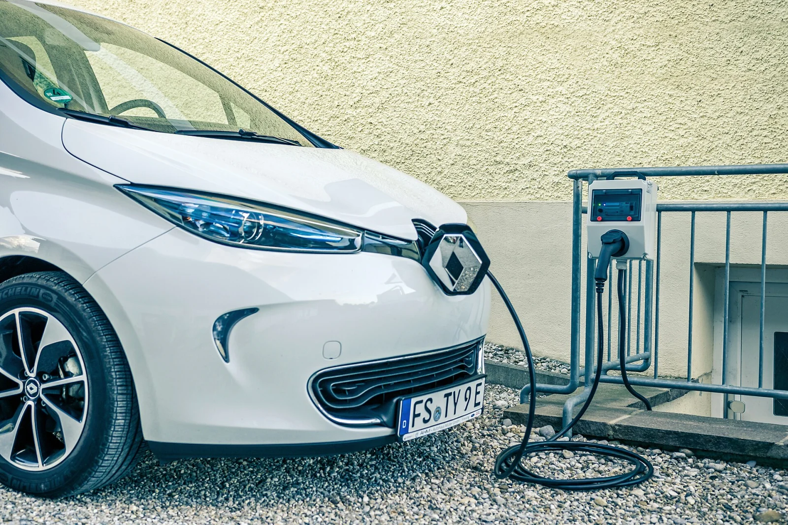 Renault Zoe reliée par un câble à une borne de recharge murale.